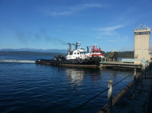 Two tugs push on the platform that holds the control tower at the Hood Canal Bridge to exert pressure on the drawspan and keep it in alignment with the bridge. State Department of Transportation