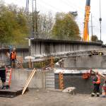 A crew from Ness Cranes of Seattle hoists the last of four 148-foot reinforced concrete beams into place Thursday for what will become the new Old Olympic Highway bridge spanning McDonald Creek west of Sequim. The new bridge replaces a narrower 1957-vintage span considered too narrow and inadequate for modern traffic. Completion of the project, coordinated by Tacoma-based Orion Marine Contractors Inc., is expected in late winter. (Keith Thorpe/Peninsula Daily News)