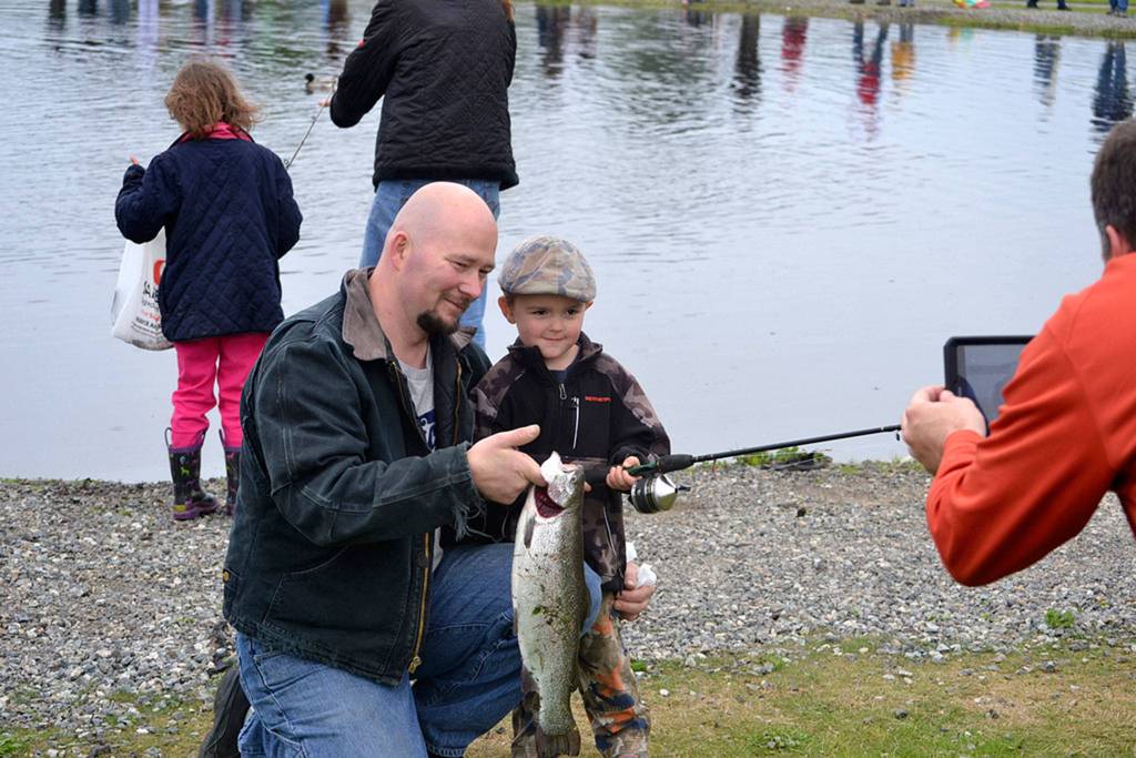 Father and son Carl and Kenneth Cook of Sequim show off Kenneth&rsquo;s first fish for a photo at Kids Fishing Day in Carrie Blake Community Park in 2016. Organizers are considering moving the pond to keep the fish healthy and safe as conditions fluctuate in the current pond. (Matthew Nash/Olympic Peninsula News Group)