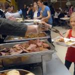 Volunteer Ellie Karjalainen, 7, of Port Angeles, right, helps with a to-go container of food during Thursdays community Thanksgiving dinner in the gym of Queen of Angels Catholic Church in Port Angeles. (Keith Thorpe/Peninsula Daily News)
