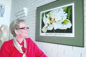 Port Angeles artist Karen Sistek looks at a framed version of a poster she created for the Skagit Valley Tulip Festival last April. Keith Thorpe/Peninsula Daily News