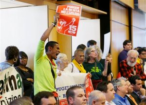 Carlos Hernandez-Sosa holds a sign in support of the $15 minimum wage measure at Monday's Seattle City Council meeting. The Associated Press