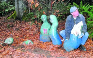 Jim Breitbach of the Port Angeles Parks Department picks up a damaged ceramic figurine by Texas artist Vida Jones on Wednesday at the Webster's Woods outdoor art park at the Port Angeles Fine Arts Center. Keith Thorpe/Peninsula Daily News