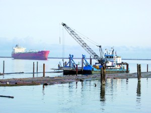The floating derrick Sea Horse works amid the log booms in Port Angeles Harbor near the Boat Haven breakwater. Thats the oil tanker Alpine Mystery anchored in the harbor at left. -- Photo by David G. Sellars/for Peninsula Daily News