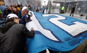 Seattle Seahawks fans sign a 25-foot by 35-foot 12th Man flag today at the base of the Space Needle in Seattle. The flag