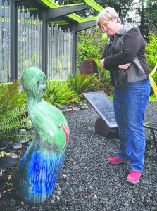 Port Angeles Fine Arts Center executive director Robin Anderson looks at a ceramic figurine by Texas artist Vida Jones that was recently moved to center's courtyard. Keith Thorpe/Peninsula Daily News
