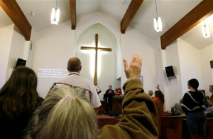 A member of the congregation at Glad Tidings Assembly of God church in Darrington raises her hand as she sings during Sunday morning church services. Much of the music and speaking was devoted to reaction to the deadly mudslide that hit the nearby community of Oso. The Associated Press
