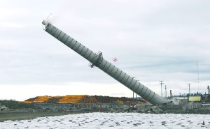 The smokestack at the former Peninsula Plywood mill falls to the ground after crews weakened the base and pulled the structure down with a cable after explosives failed to do the job. Keith Thorpe/Peninsula Daily News