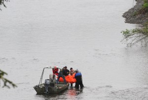The body discovered Saturday afternoon is taken to a jet boat by authorities on the Bogachiel River near Leyndecker Park east of LaPush. Lonnie Archibald/for Peninsula Daily News
