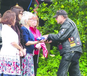 Betsy Reed Schultz is presented with a flag by a member of the American Legion Post 29 Sunday in Port Angeles. Arwyn Rice/Peninsula Daily News