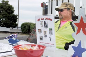 Bill Berger sits at a table he and friends and family set up at Port Angeles City Pier on Friday afternoon to distribute information about the importance of crisis-intervention training for law enforcement officers. Photo by Jeremy Schwartz/Peninsula Daily News