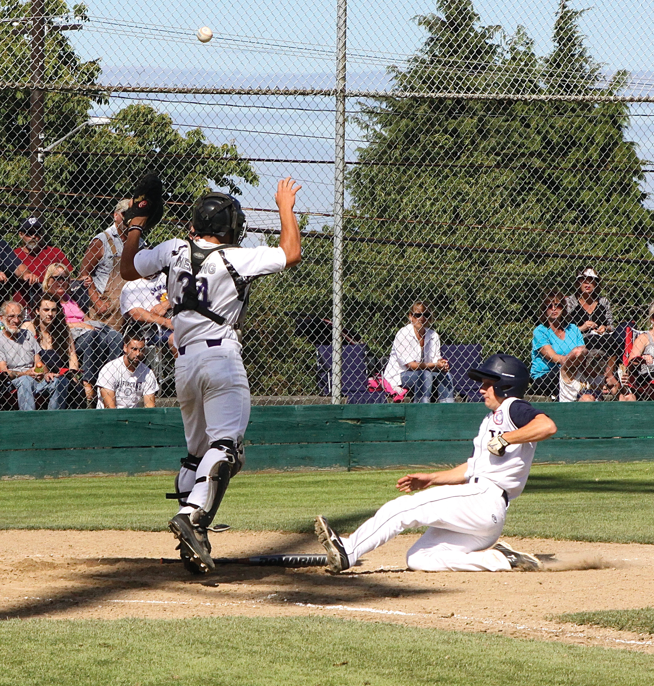 Wilder's Brett Wright slides safely into home as the throw gets by Oak Harbor catcher Robert Herring. Dave Logan/for Peninsula Daily News