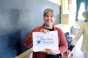 Museum & Arts Center spokeswoman Judy Stipe shows off the sign marking the Sequim museum's new Blue Star designation. Joe Smillie/Peninsula Daily News