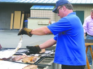 Rotarian Jay Patton checks the temperature on salmon baking on an outdoor grill at Sunday's Sequim Rotary salmon bake