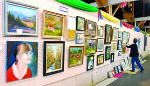 Volunteer Mary Marsh of Sequim arranges artworks in the Artists Building at the Clallam County Fairgrounds on Tuesday. The Clallam County Fair begins its four-day run starting on Thursday in Port Angeles. Keith Thorpe/Peninsula Daily News