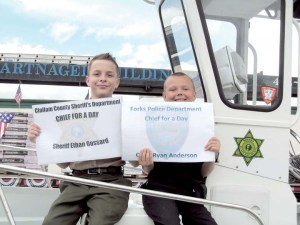 Clallam County Sheriff for a Day Ethan Gossard and Forks Police Chief for a Day Ryan Anderson ride in the Clallam County Sheriff's Office's patrol boat at the Forks Old Fashioned Fourth of July Parade. Clallam County Sheriff's Office