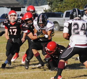 Neah Bay's Elisha Winck (28) and Josh Monette (11) team up to bring down Lummi's Devin Cooper (9) as Neah Bay's Tommy Tyler (17) and John Reamer join the fray. Lonnie Archibald/for Peninsula Daily News