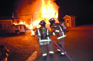 Firefighter-paramedics Brian Ouellette and Joel McKeen of Clallam County Fire District No. 3 prepare to attack a motor home fire on North Barr Road on Wednesday. Patrick Young/Clallam County Fire District No. 3