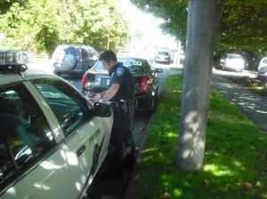Port Angeles Deputy Police Chief Brian Smith fills out paperwork on the hood of a State Patrol car after hitting a Cadillac parked on Peabody Street with his squad car Monday. Margaret McKenzie/Peninsula Daily News