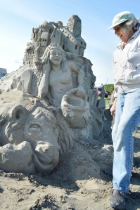 Kali Bradford inspects her rebuilding efforts on her vandalized sand sculpture "Violet Picking Lavender" in Sequim. Joe Smillie/Peninsula Daily News