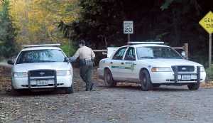 Clallam County Sheriff's Deputy Amy Bundy confers with another deputy while guarding the access to Lower Dam Road west of Port Angeles today after a body was found in the woods near the site of the former Elwha Dam. Keith Thorpe/Peninsula Daily News