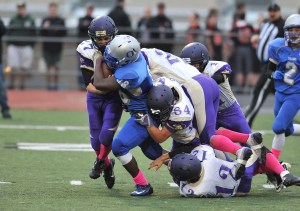 Olympic's R.J. Enriquez (48) is slowed by a pack of Sequim Wolves