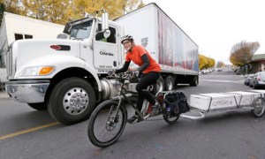 Heidi Lappetito pedals her cargo bike past a parked beer truck as she hauls a trailer loaded with frozen salmon in Port Townsend. The Associated Press