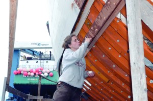 Volunteer Alea Robertson taps bungs  used to smooth over holes left by fasteners that bind planks to a vessel  into the hull of the Adventuress.  Charlie Bermant/Peninsula Daily News