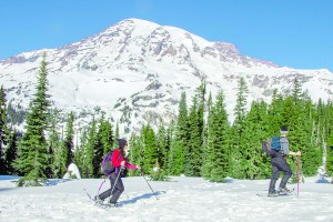 People snowshoe near Paradise in view of Mount Rainier in January. State officials are monitoring lower than usual snowpack levels this winter.  The Associated Press