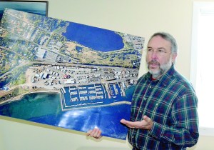 Port of Port Townsend Commissioner Steve Tucker holds an aerial shot of the Boat Haven during a meeting Wednesday. Closing a lane along the water will free up several parking spaces that will be able to accommodate peak season overflow.  Charlie Bermant/Peninsula Daily News