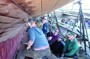 Alea Robertson screws in the last plank for the schooner Adventuress five year renovation under the watchful eyes of (from left) Sound Experience board chair Kenneth Greff