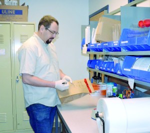 Port Townsend Police Detective Jason Greenspane demonstrates the process that will be used to return items of stolen mail to the U.S. Postal Service.  Charlie Bermant/Peninsula Daily News