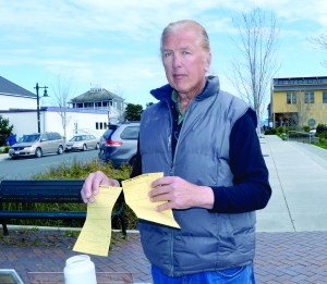 Richard Erik Olson displays the two summons he received Monday for being out of compliance with the city of Port Townsends recently approved sign code.  Charlie Bermant/Peninsula Daily News