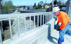 Alan Lubich of Seattle-based SB Structures checks the level on a guardrail of the new Lauridsen Boulevard bridge in Port Angeles.  Keith Thorpe/Peninsula Daily News