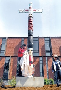 Totem pole restorer Terry Johnson pulls the cover from a totem pole during Tuesday's unveiling ceremony near Maier Hall on the Port Angeles campus of Peninsula College. Assistant Kirby Jock stands at right. — Keith Thorpe/Peninsula Daily News