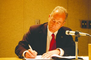 Jeff Robb signs his new contract at this morning's Port of Port Angeles Board of Commissioners meeting.  -- Photo by Paul Gottlieb/Peninsula Daily News
