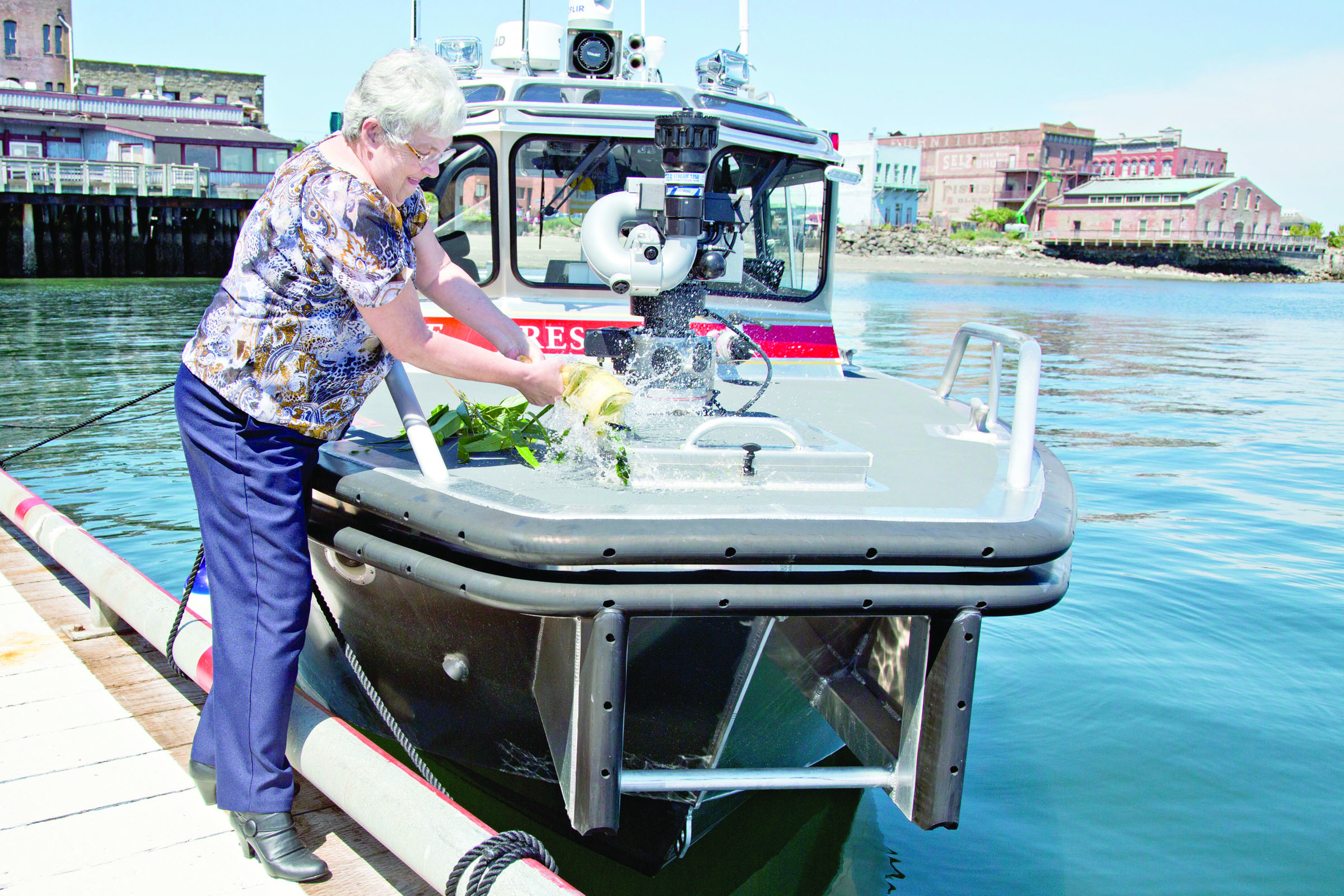 Retiring East Jefferson Fire Rescue secretary Lonibeth Harbison christens the new firefighting boat Guardian on Wednesday afternoon.  Crystal Craig/East Jefferson Fire Rescue