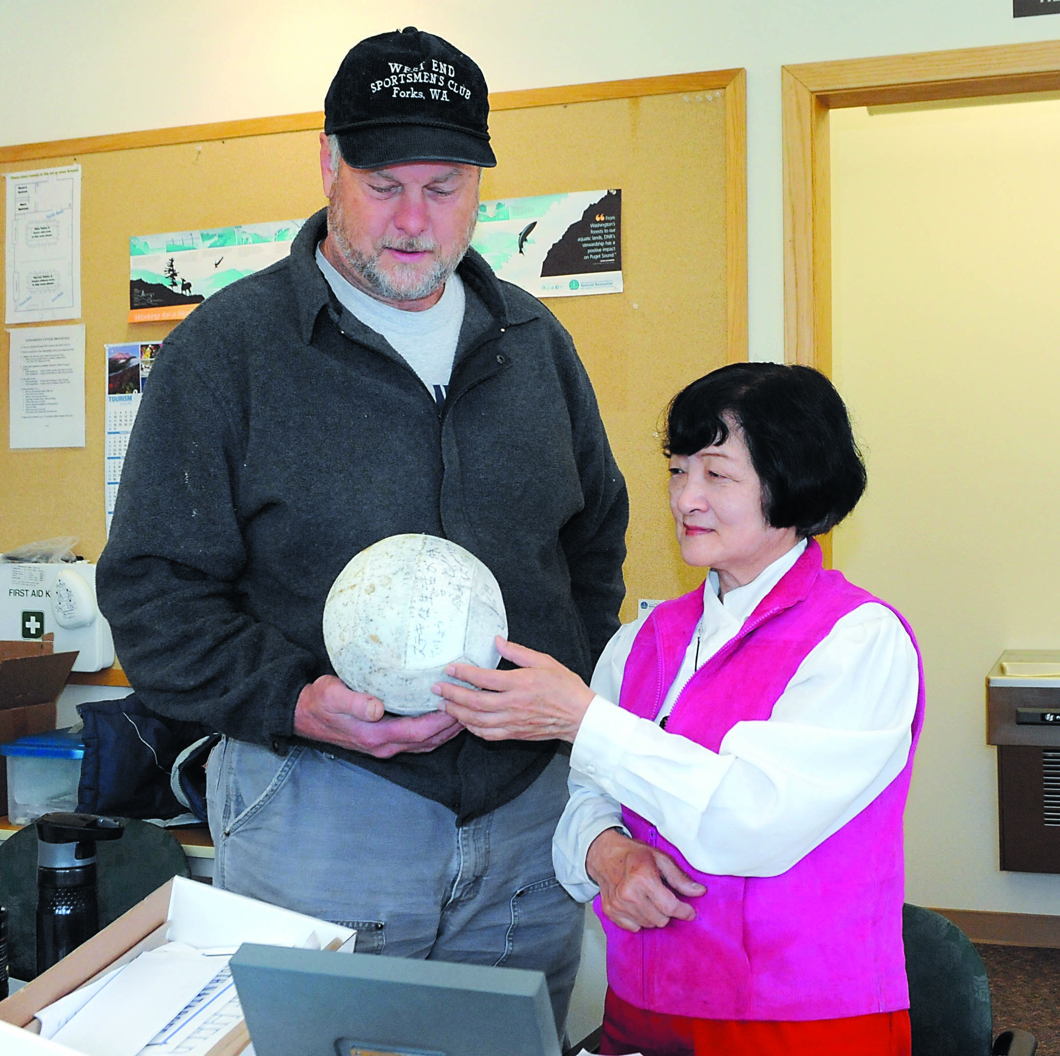 Reiko Barclay of Sequim deciphers the writing on this volleyball found by John Anderson of Forks.  -- Photo by Lonnie Archibald/for Peninsula Daily News