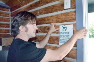 Greg Brotherton hangs a sign outlining rules for customers inside Sea Change Cannabis in Discovery Bay in preparation for his eventual opening. —Photo by Charlie Bermant/Peninsula Daily News