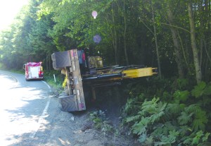 The tractor-trailer carrying this excavator rolled onto the side of state Highway 112 on Monday afternoon. Washington State Patrol