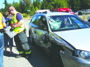Emergency personnel from Clallam County Fire District discuss a two-vehicle crash that occurred Sunday afternoon at the intersection of Dan Kelly and Place roads with state Highway 112. Drivers of both vehicles were treated and released at the scene.  Clallam County Fire District No. 2