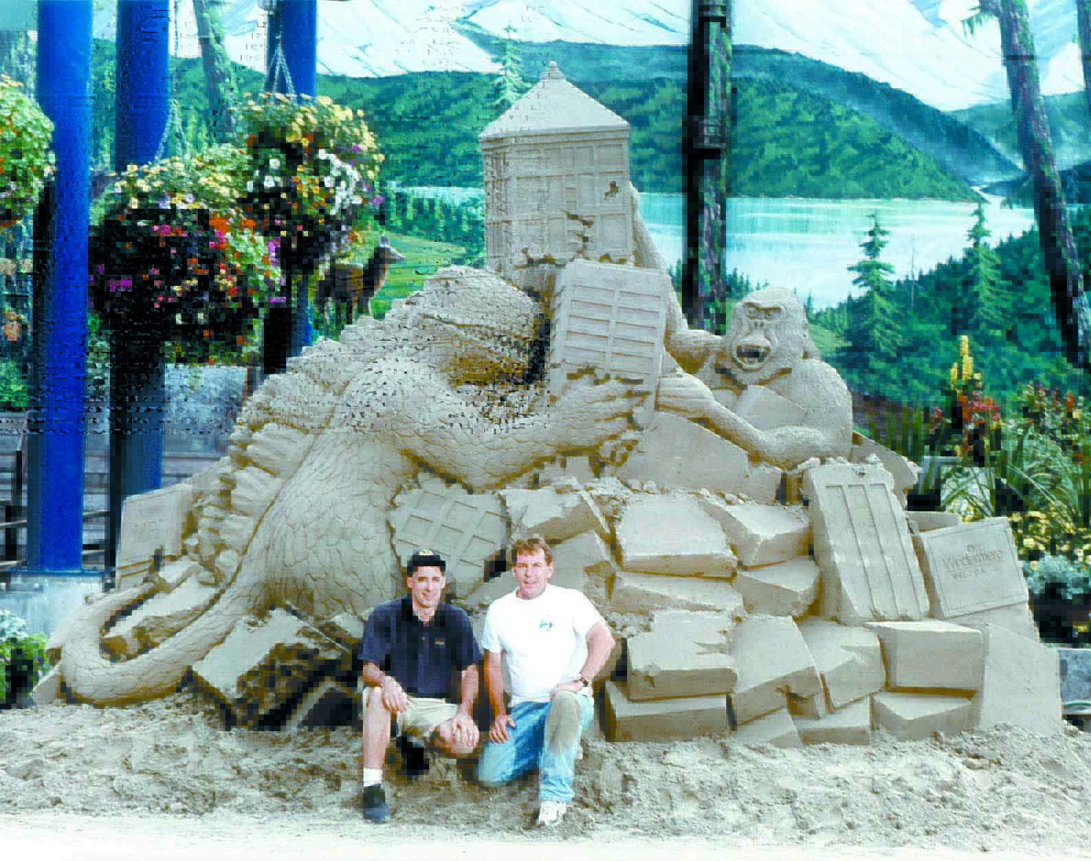 Sand sculptors Andrew Briggs of Victoria and Charlie Beaulieu of Kingston sit in front of their sand sculpture of Godzilla and King Kong at the Conrad Dyar Memorial Fountain in downtown Port Angeles in this August 2001 file photo. Keith Thorpe/Peninsula Daily News