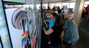 Visitors to the Space Needle in Seattle interact with a large touch-screen photo display wall that lets visitors see historical photos as well as photos shared by other visitors. — Photo by Ted S. Warren/The Associated Press