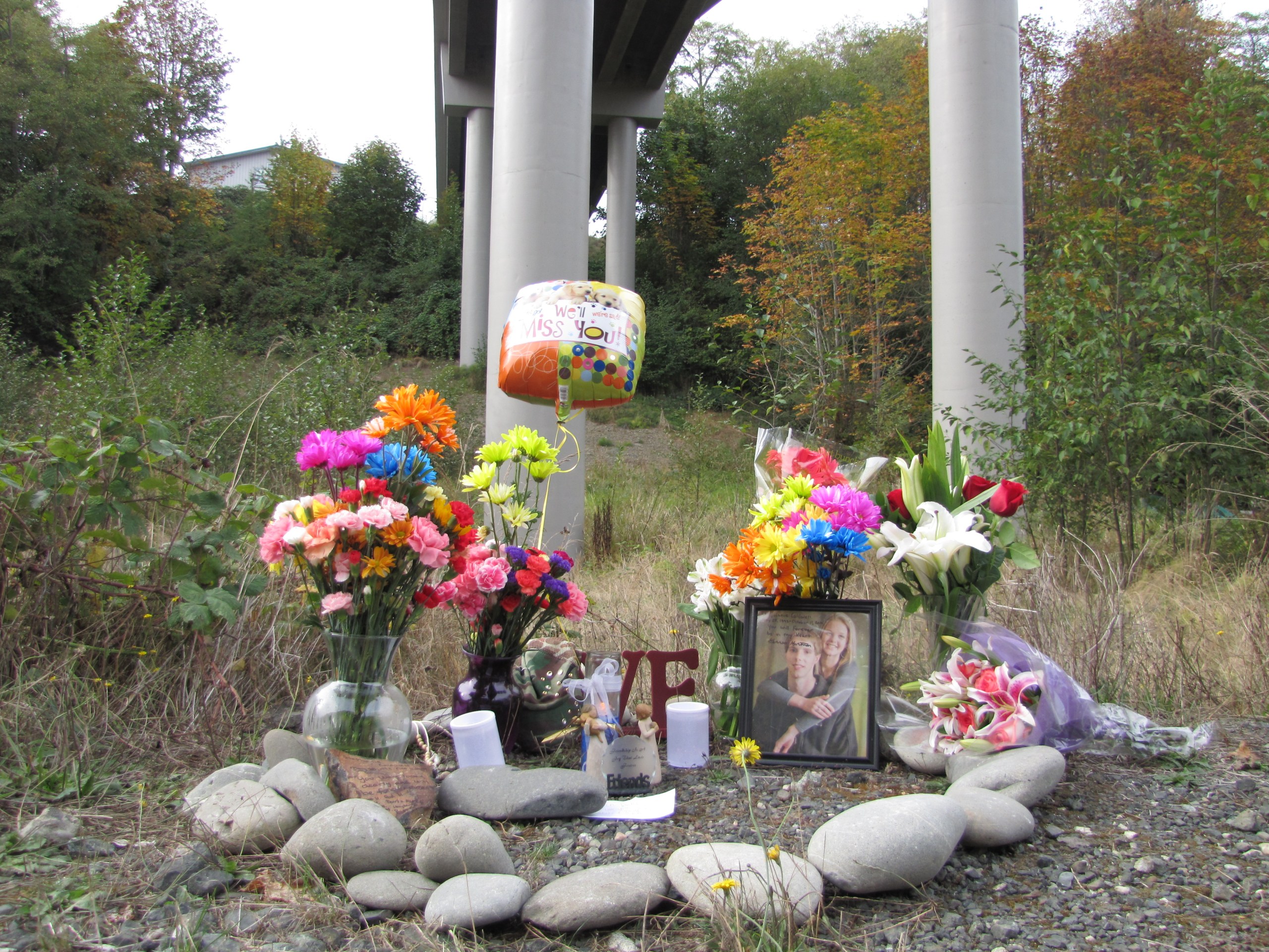 A memorial to Stephanie Diane Caldwell sits late Monday below the Eighth Street bridge from which the 21-year-old woman plunged Saturday. —Photo by Arwyn Rice/Peninsula Daily News