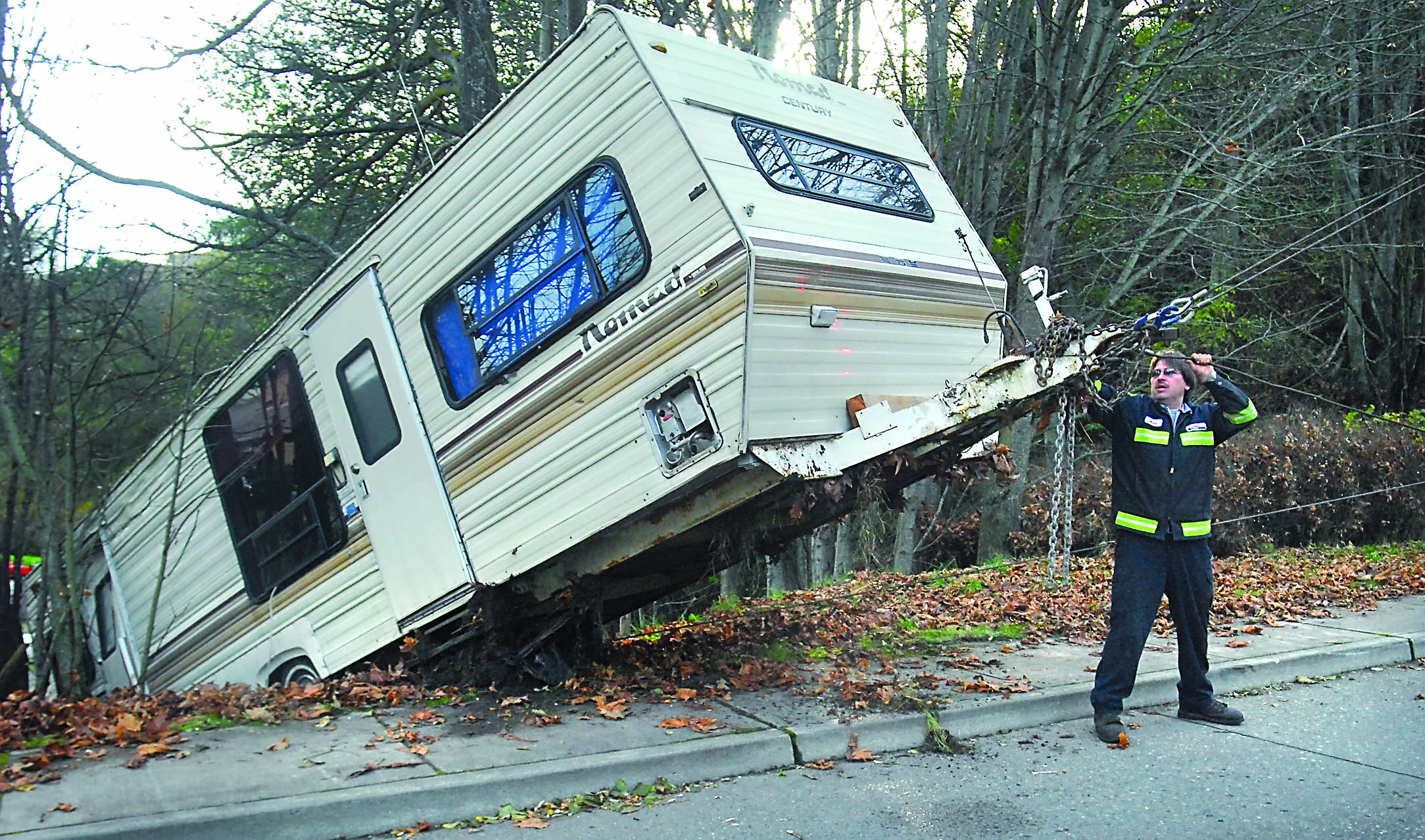 Hans Schmitt of Evergreen Towing attaches a tow cable to a 30-foot travel trailer that broke loose from the vehicle pulling it and careened down the hill on Cedar Street and over an embankment on Friday morning in Port Angeles. The driver of the vehicle pulling the trailer fled the scene.  -- Photo by Keith Thorpe/Peninsula Daily News