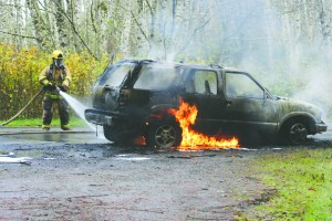 A firefighter with Clallam County Fire District No. 4 works on a vehicle fire along state Highway 112 near Gossett Road on Monday at about 11 a.m. The driver