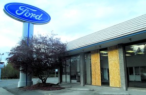 Plywood panels cover portions of the former Price Ford Lincoln showroom on East Front Street in Port Angeles after the windows were shot out midday Friday.  -- Photo by Keith Thorpe/Peninsula Daily News