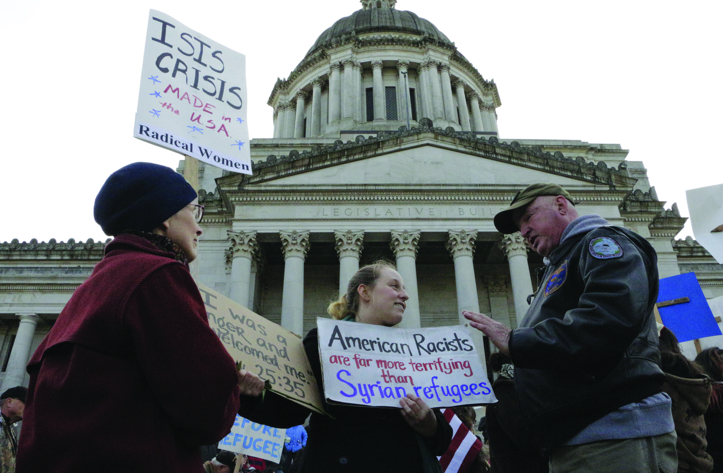 Protesters on opposing sides of the Syrian refugee resettlement issue rally in front of the state Capitol in Olympia on Friday. Gov. Jay Inslee has said the state will welcome refugees and has criticized other governors who have threatened to stop accepting them following last weeks terror attacks in Paris.  The Associated Press