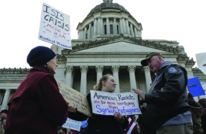 Protesters on opposing sides of the Syrian refugee resettlement issue rally in front of the state Capitol in Olympia on Friday. Gov. Jay Inslee has said the state will welcome refugees and has criticized other governors who have threatened to stop accepting them following last weeks terror attacks in Paris.  The Associated Press
