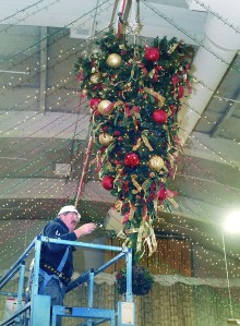 Harry Hebert works from a lift as he adds a string of lights Tuesda to a Christmas tree that hangs upside-down from the ceiling as part of the decorations at Vern Burton Community Center in Port Angeles. Photo by Keith Thorpe/Peninsula Daily News